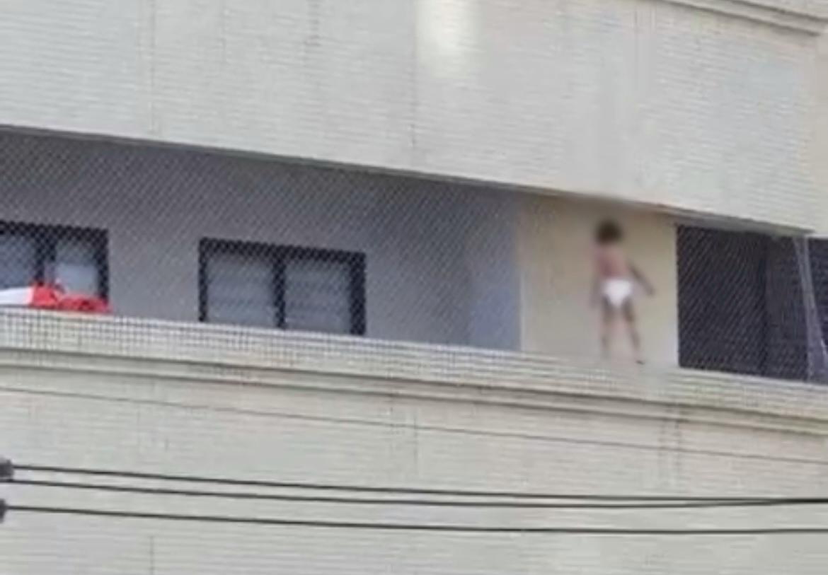 Criança brinca e se apoia em tela de proteção de sacada de prédio de Maringá; VÍDEO