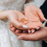 Groom holds bride’s hands, where are two wedding rings