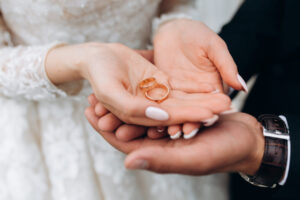 Groom holds bride’s hands, where are two wedding rings