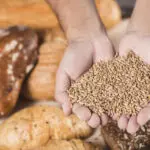 overhead-view-hands-holding-wheat-grains-baked-bread