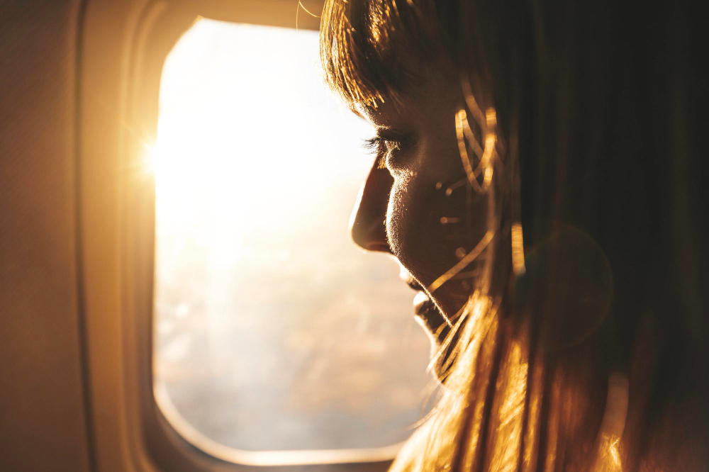 young-woman-looking-through-window-airplane