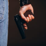 Handsome man actor posing in studio with weapon