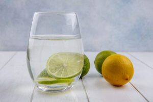 front view water in a glass with lime and lemon on a white background