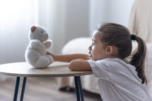 A little girl plays with her teddy bear.