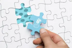 close-up-human-hand-holding-blue-puzzle-piece-with-brain-cogwheel-drawing