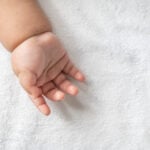 Newborn baby hand in white bed