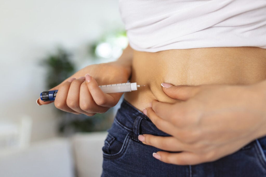 A diabetic patient using insulin pen for making an insulin injection at home. Young woman control diabetes. Diabetic lifestyle