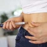 A diabetic patient using insulin pen for making an insulin injection at home. Young woman control diabetes. Diabetic lifestyle