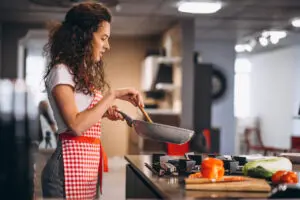 Woman chef cooking vegetables in pan