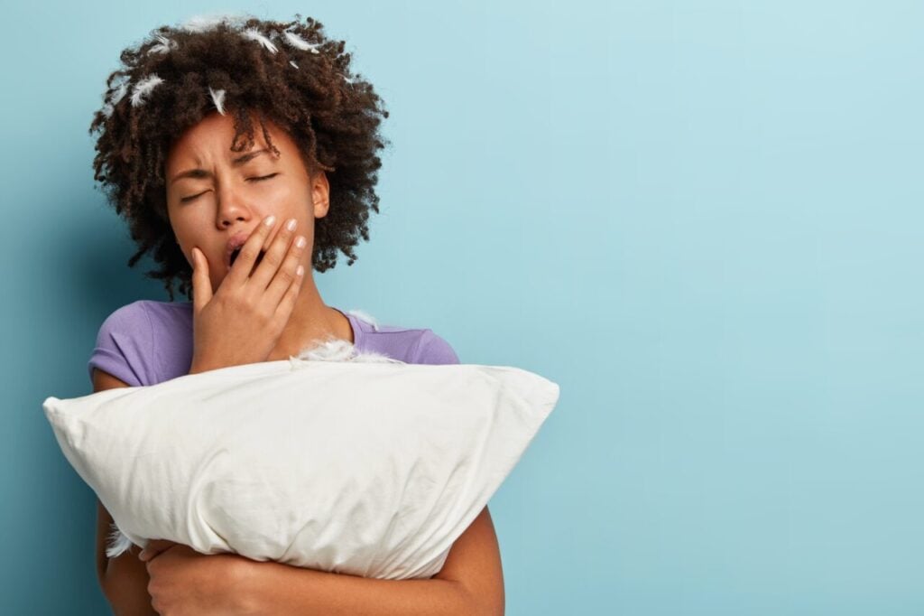 young-brunette-woman-with-feathers-hair-holding-pillow