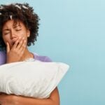 young-brunette-woman-with-feathers-hair-holding-pillow