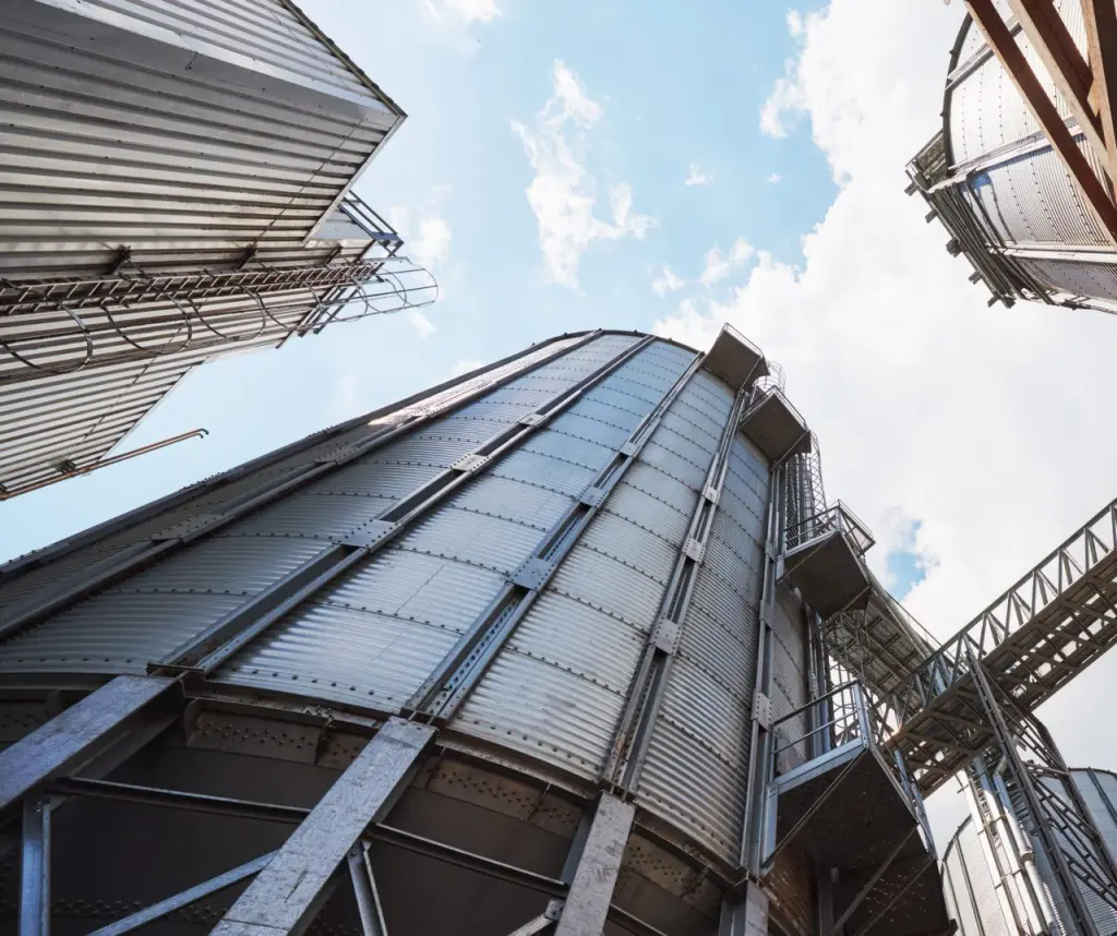 Agricultural Silos. Building Exterior. Storage and drying of grains, wheat, corn, soy, sunflower against the blue sky with white clouds