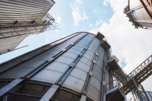Agricultural Silos. Building Exterior. Storage and drying of grains, wheat, corn, soy, sunflower against the blue sky with white clouds