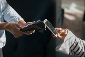 mulher fazendo pagamento em maquininha usando aproximacao do celular