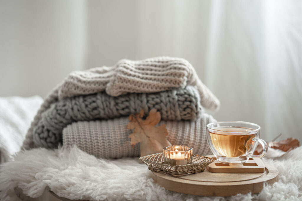 Cozy autumn composition with a stack of knitted sweaters and tea.