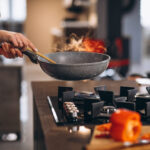 Woman chef cooking vegetables in pan
