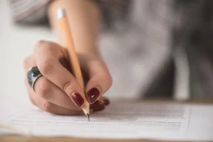 mão em destaque de mulher fazendo prova de concurso foto freepik