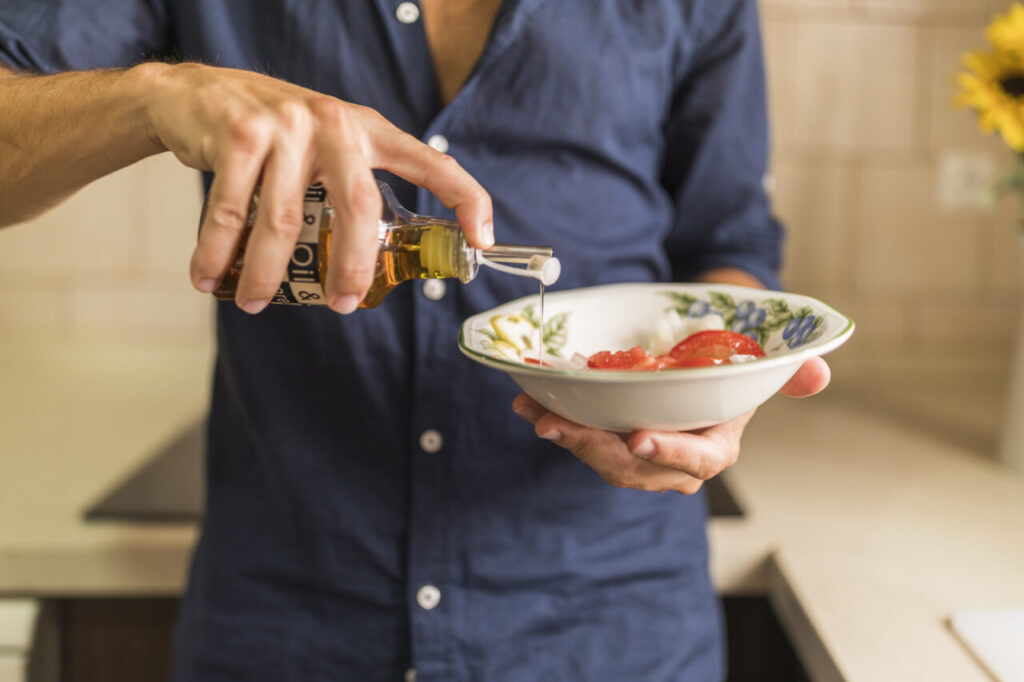 close-up-de-homem-vestindo-salada-com-azeite-oliva-em-tigela