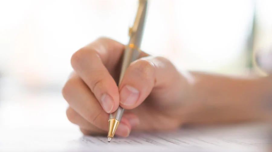 Hand with pen over application form