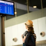 Woman in front of airport flight information panel