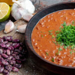 classic-tomato-soap-beans-garlic-spoon-wooden-cutting-board-oil-bottle-lemon-vertical-view