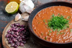 classic-tomato-soap-beans-garlic-spoon-wooden-cutting-board-oil-bottle-lemon-vertical-view