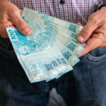 Homem segurando notas brasileiras de 100 reais imagem istock