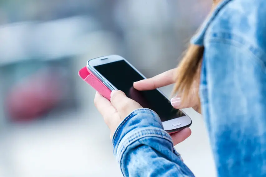 Mobile phone in a woman’s hand. Outdoor image.