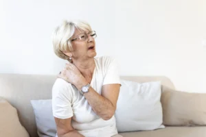 Close up of sad senior lady with neckache. Senior woman with chronic pain syndrome fibromyalgia suffering from acute neckaches. Senior woman suffering from neck pain