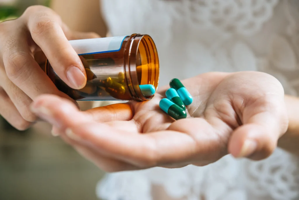 Woman’s hand pours the medicine pills out of the bottle